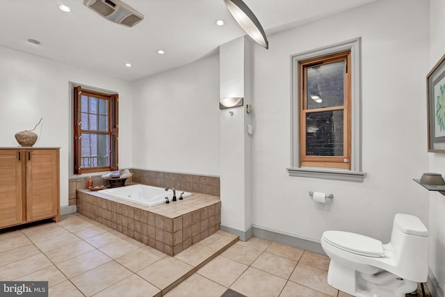 bathroom featuring tiled tub, toilet, and tile patterned flooring