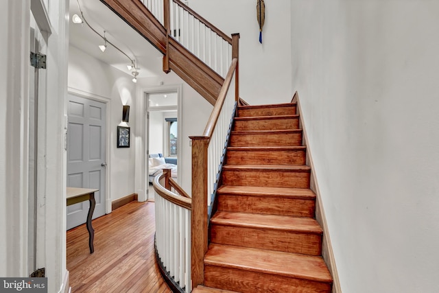 staircase featuring hardwood / wood-style floors and rail lighting