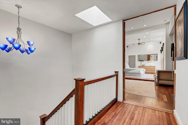 hallway featuring an inviting chandelier, a skylight, and wood-type flooring