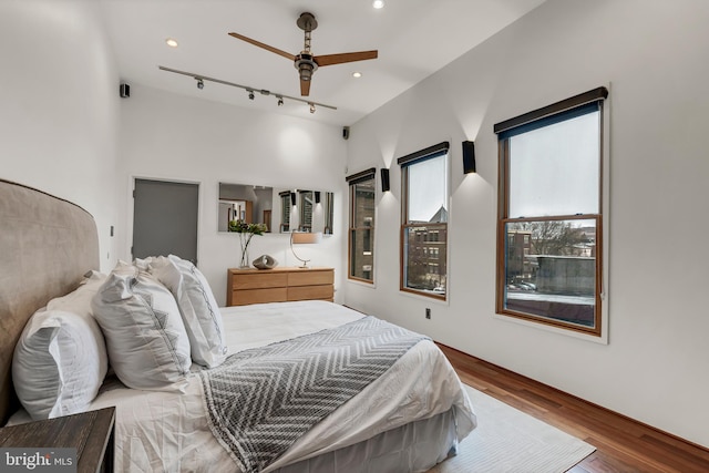 bedroom with ceiling fan, hardwood / wood-style flooring, and track lighting