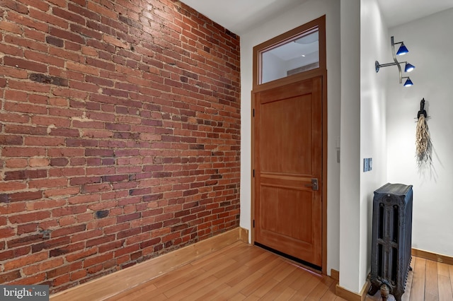 entrance foyer featuring brick wall, radiator, and light wood-type flooring