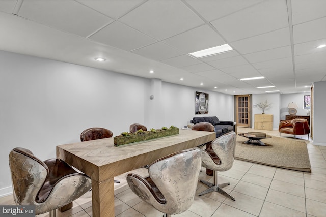 dining area with a drop ceiling and light tile patterned flooring