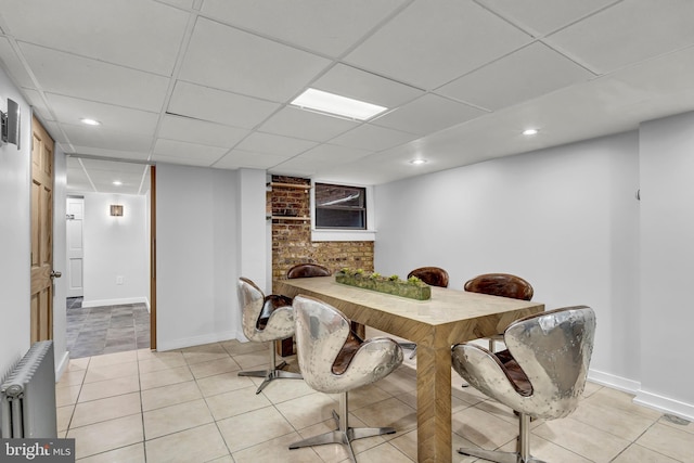 tiled dining room with radiator heating unit and a paneled ceiling