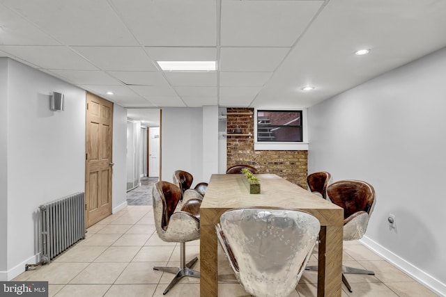 dining area with a paneled ceiling, light tile patterned floors, and radiator