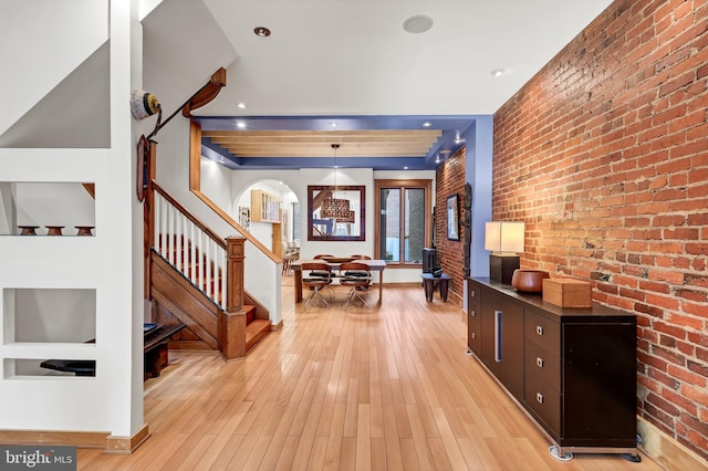 entryway with light wood-type flooring and brick wall