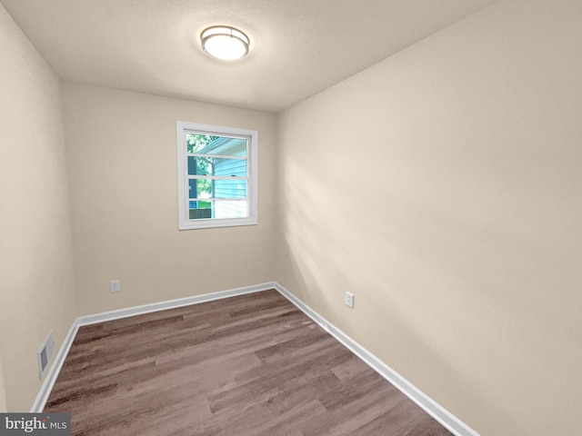 unfurnished room featuring visible vents, baseboards, and wood finished floors