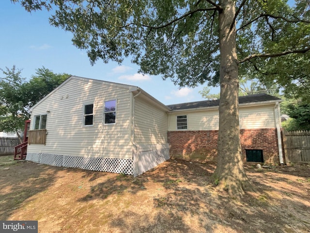 view of property exterior featuring brick siding and fence