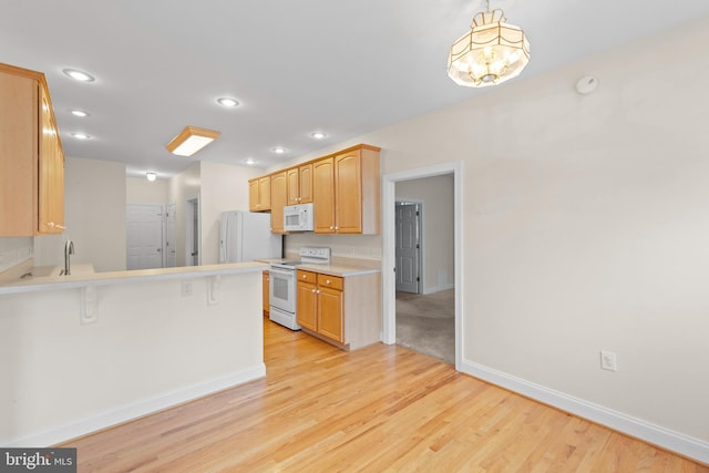 kitchen with a breakfast bar, white appliances, kitchen peninsula, and light hardwood / wood-style flooring