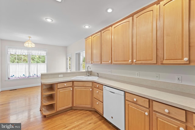 kitchen with light wood-type flooring, dishwasher, sink, kitchen peninsula, and hanging light fixtures