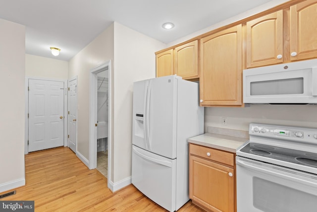 kitchen with light hardwood / wood-style floors, white appliances, and light brown cabinets