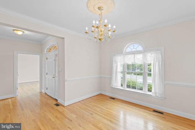 empty room with ornamental molding, an inviting chandelier, and hardwood / wood-style flooring