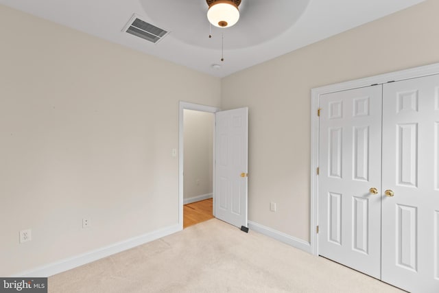 unfurnished bedroom with ceiling fan, light colored carpet, and a closet