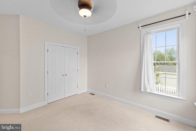 unfurnished bedroom with light carpet, ceiling fan, and a closet