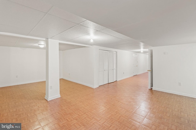 basement with light parquet floors and a paneled ceiling