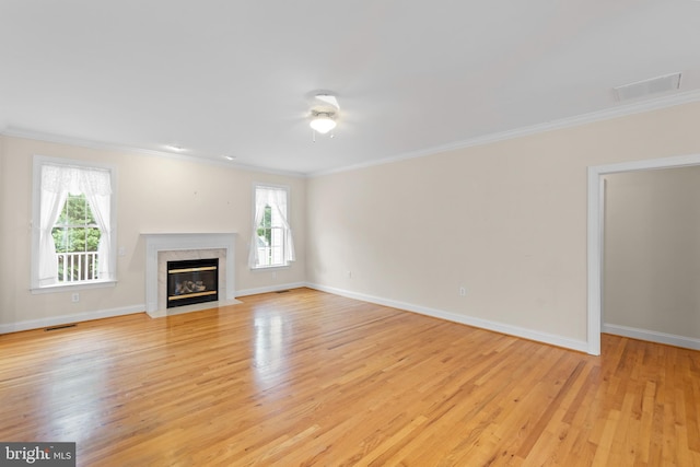 unfurnished living room featuring light wood-type flooring, a fireplace, ornamental molding, and ceiling fan