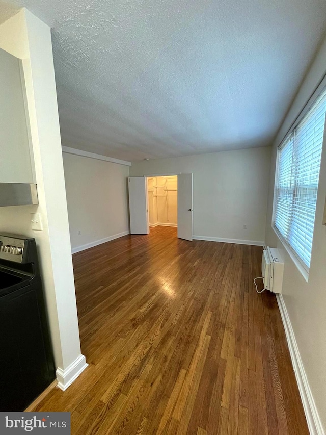 unfurnished living room with a textured ceiling and dark hardwood / wood-style floors