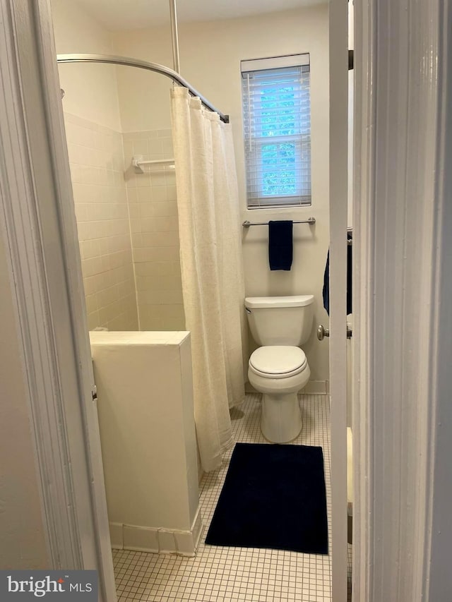 bathroom with tile patterned floors, a shower with shower curtain, and toilet