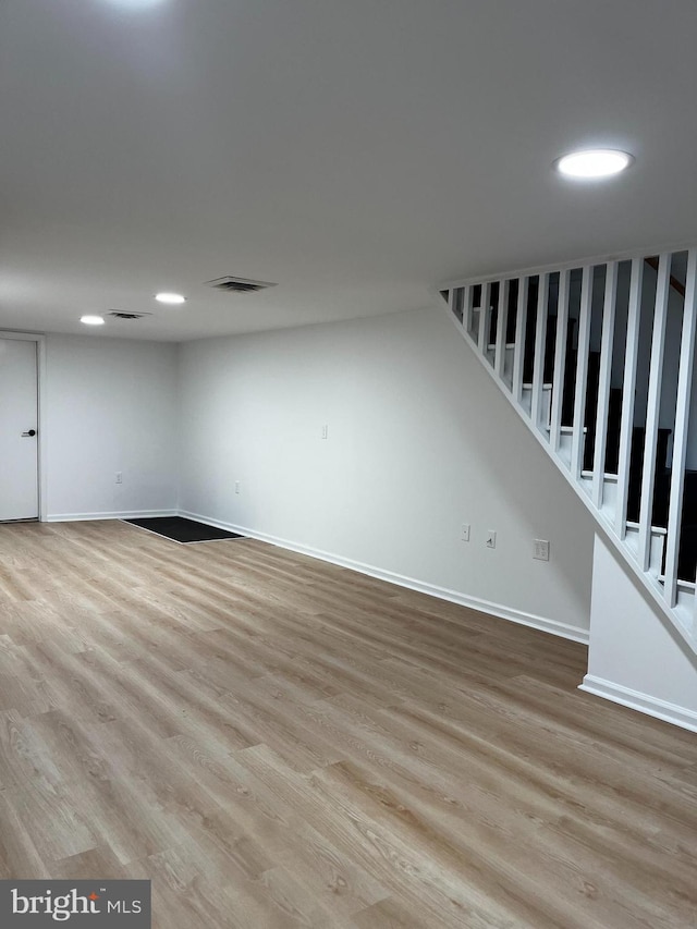 below grade area featuring baseboards, visible vents, stairs, light wood-style floors, and recessed lighting