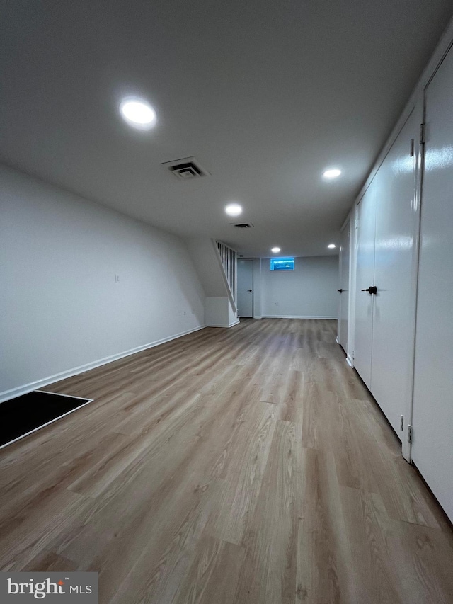 finished basement featuring light wood-style floors, baseboards, visible vents, and recessed lighting