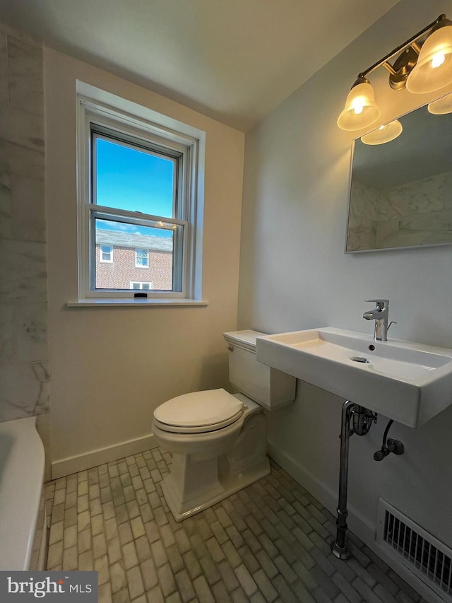 bathroom with toilet, brick floor, visible vents, and baseboards