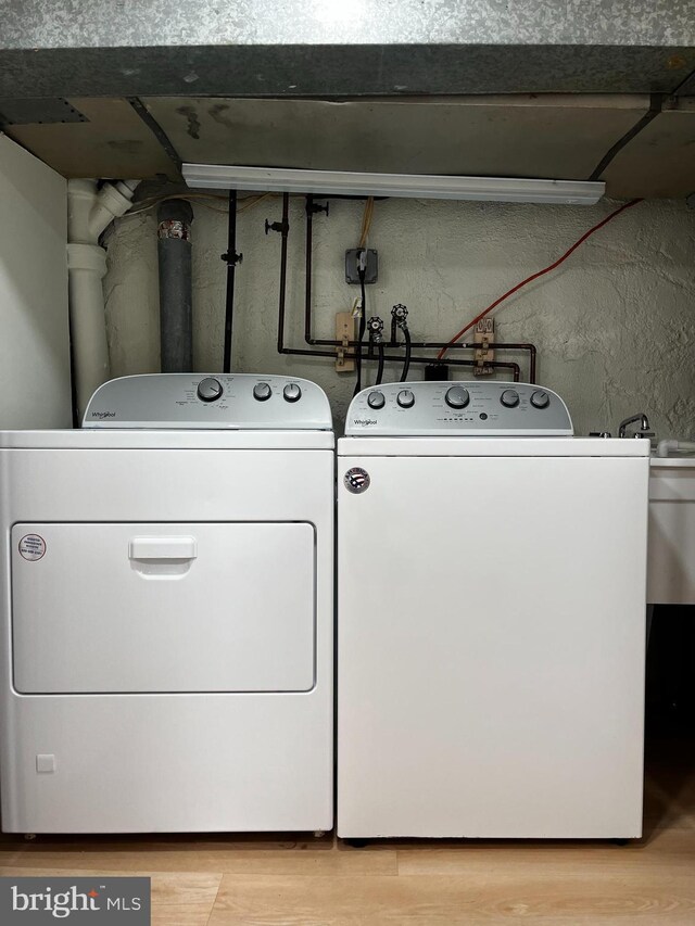 washroom featuring washing machine and clothes dryer and light hardwood / wood-style flooring