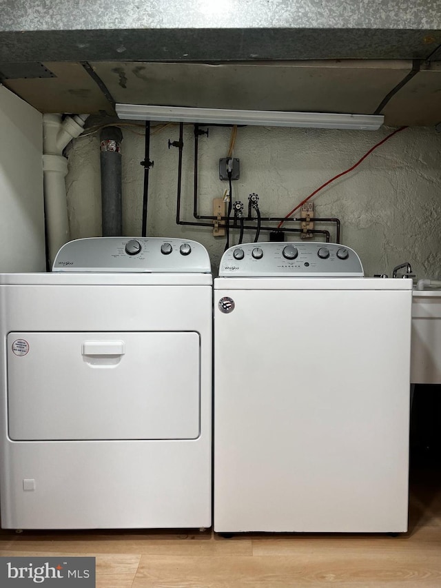 clothes washing area with light wood-style floors and washer and dryer