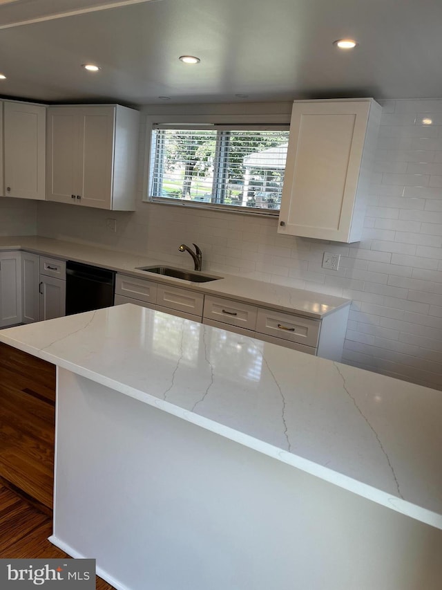 kitchen with light stone counters, recessed lighting, a sink, white cabinets, and dishwasher