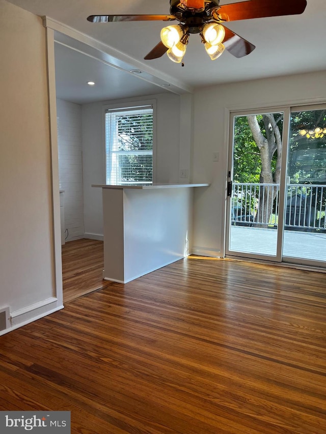 unfurnished room with baseboards, ceiling fan, wood finished floors, and a healthy amount of sunlight