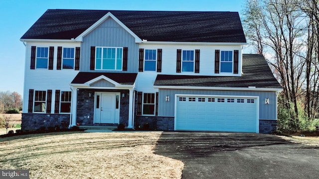 view of front facade featuring board and batten siding, stone siding, an attached garage, and aphalt driveway