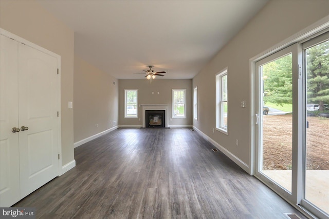 unfurnished living room with dark hardwood / wood-style flooring and ceiling fan