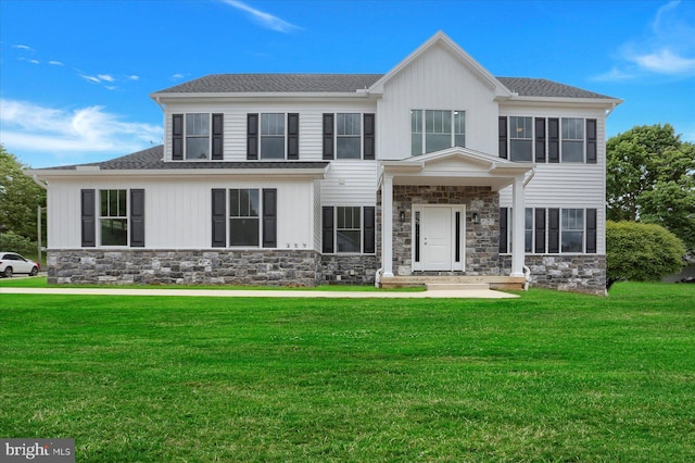 view of front facade featuring stone siding, a shingled roof, and a front yard