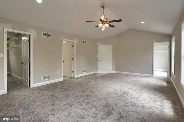 unfurnished bedroom featuring ceiling fan, carpet flooring, a closet, lofted ceiling, and a spacious closet