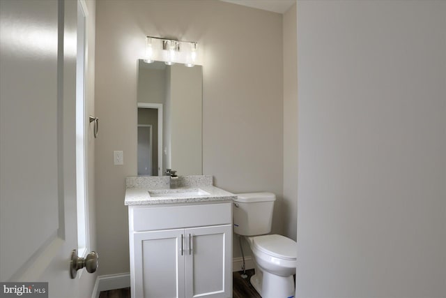 bathroom featuring wood-type flooring, toilet, and vanity