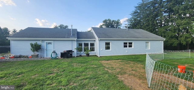 back of house featuring a yard, roof with shingles, and fence