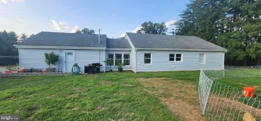 rear view of house featuring fence and a lawn