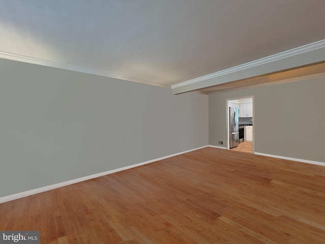 spare room with baseboards, crown molding, and light wood-style floors