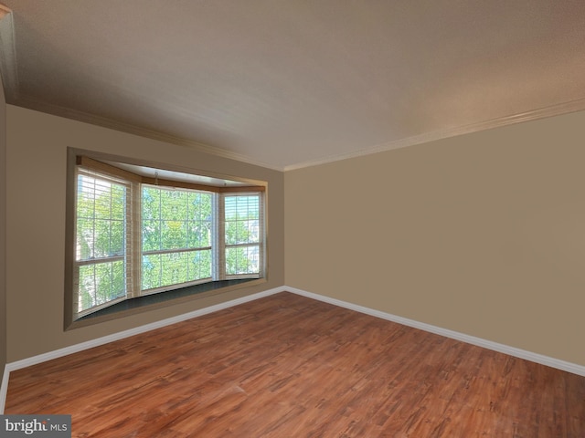 spare room featuring crown molding, baseboards, and wood finished floors