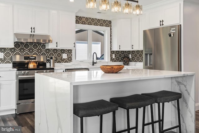 kitchen featuring ventilation hood, white cabinetry, appliances with stainless steel finishes, and decorative light fixtures