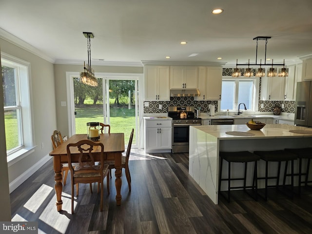 kitchen featuring white cabinets, hanging light fixtures, stainless steel appliances, and dark hardwood / wood-style flooring