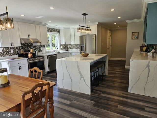 kitchen with white cabinets, appliances with stainless steel finishes, pendant lighting, and dark hardwood / wood-style flooring