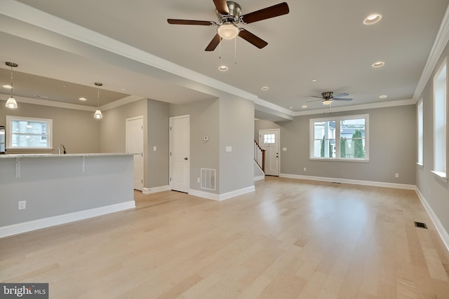 unfurnished living room featuring ceiling fan, sink, crown molding, and light hardwood / wood-style floors