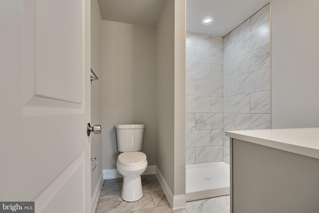 bathroom featuring a tile shower, vanity, and toilet