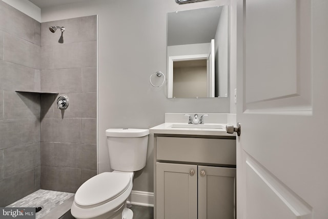 bathroom with vanity, toilet, and tiled shower