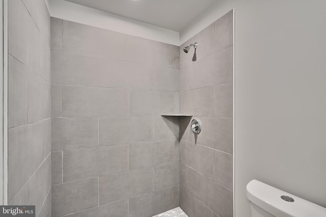 bathroom with tiled shower and toilet