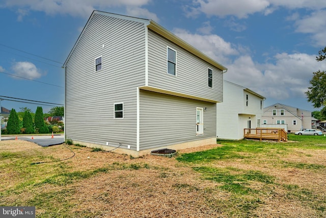 back of house featuring a lawn and a wooden deck