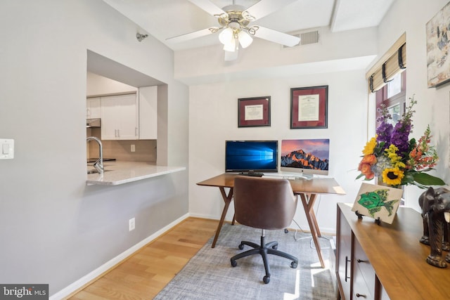 home office featuring ceiling fan, light wood-type flooring, and sink