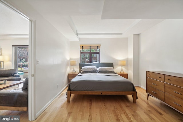 bedroom featuring a tray ceiling and light hardwood / wood-style floors