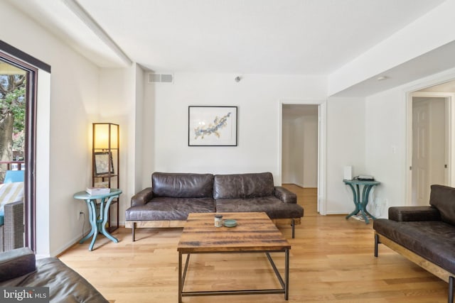 living room featuring baseboards, visible vents, and light wood finished floors