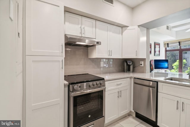 kitchen featuring appliances with stainless steel finishes, white cabinetry, under cabinet range hood, and light stone counters