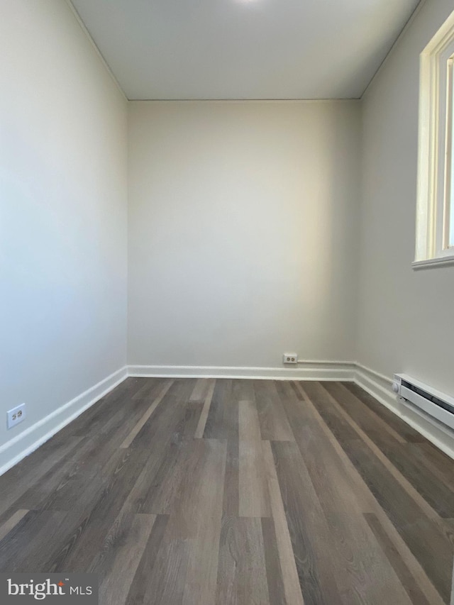 spare room with baseboard heating and dark wood-type flooring